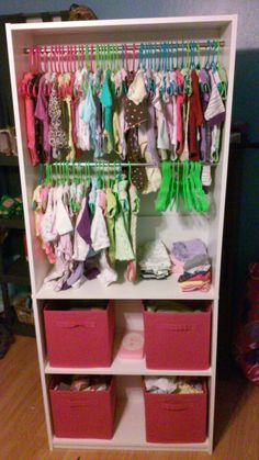 a closet filled with lots of clothes and pink bins on top of the shelves