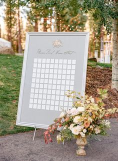 a sign with a calendar on it sitting next to a bouquet of flowers and greenery