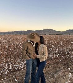 a man and woman standing in the middle of a cotton field