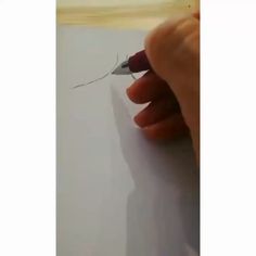 someone is drawing something on paper with a pen and inking it down the middle