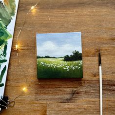 a painting is being displayed on a table with paintbrushes and other art supplies