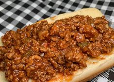 a sandwich with meat on it sitting on a checkered table cloth