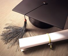 a graduation cap, tassel and diploma laying on a wooden table next to it