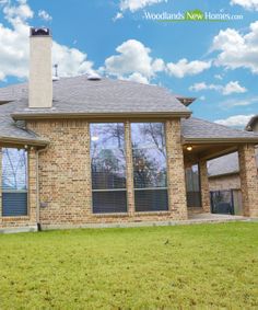 a brick house with large windows and grass in front