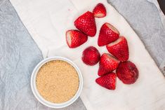 strawberries and oatmeal on a towel next to a bowl of cereal