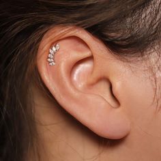 a woman's ear with three small white flowers on the top of her ear