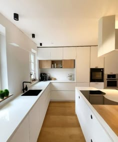 a modern kitchen with white cabinets and wood flooring on the walls, along with an island in the middle