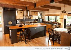 a large kitchen with wooden floors and black cabinets is pictured in this image, there are two bar stools at the center of the island