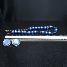 *Description: This is a great Moonglow set by Lisner from the 1950s. The medium blue moonglow Lucite beads also have Lucite clear blue faceted beads with filigree bead caps as in three sections. There are twenty-two Lucite Moonglow beads and three inches of extension chain. The Lisner tag is on one end with the hook clasp with the name Lisner on the back at the other end. The matching blue Moonglow clip on earrings are a little over an inch with the Moonglow cabochon framed in a gold tone frame. Retro Blue Jewelry For Party, Vintage Blue Jewelry For Evening, Blue Beaded Evening Jewelry, Blue Vintage Jewelry For Evening, Blue Beaded Jewelry For Evening, Retro Beaded Evening Jewelry, Retro Beaded Jewelry For Evening, Vintage Blue Jewelry For Party, Vintage Blue Necklace For Evening