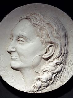 a white plaque with a woman's face in profile, on a black background