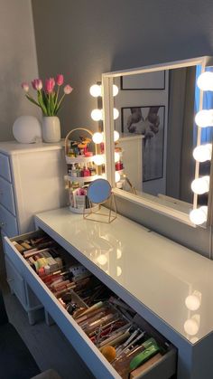 a vanity with drawers and lights on it in front of a mirror that is lit up