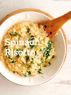 spinach risotto in a white bowl with a wooden spoon on the side