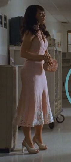 a woman in a pink dress is holding a purse