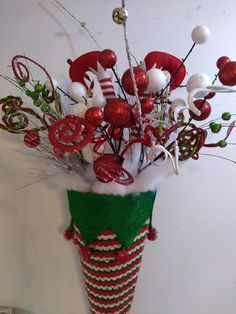 a vase filled with lots of red and white decorations on top of a table next to a wall