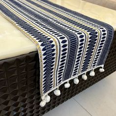 a blue and white table runner with tassels