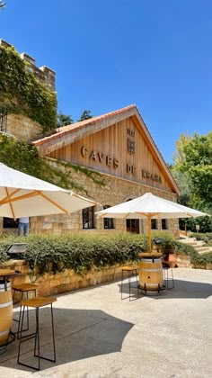 tables with umbrellas and wine barrels in front of a winery