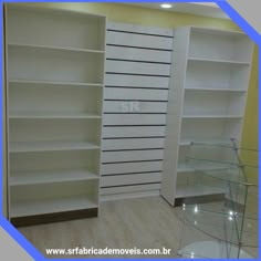 an empty room with white shelves and glass tables