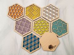 six hexagonal wooden coasters with different patterns on them, each one has a bee in the center