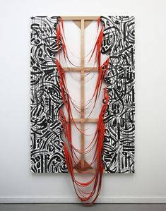 an art piece with red string hanging from it's sides