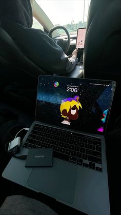 an open laptop computer sitting on top of a car seat next to a person in the driver's seat