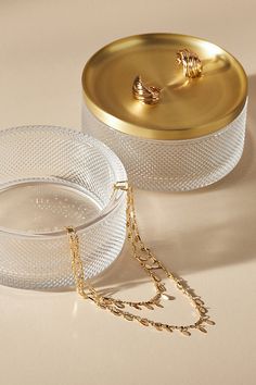 two clear dishes with gold chains on them and one has a golden chain around it