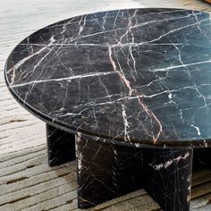 a black marble coffee table sitting on top of a carpeted floor next to a rug