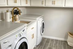 a washer and dryer in a small room with white cabinets on the walls