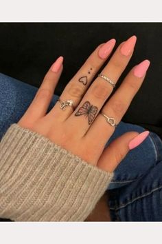 a woman's hand with three different tattoos on her fingers and two rings in the middle