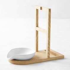 a white bowl sitting on top of a wooden stand next to a small square shaped object