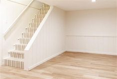 an empty room with stairs and hard wood flooring