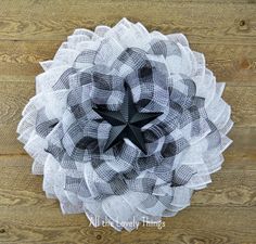 the black and white mesh flower is hanging on a wooden wall with wood planks