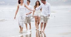 four people walking on the beach holding hands