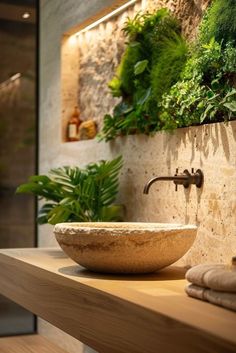 a bowl sink sitting on top of a wooden counter next to a plant filled wall