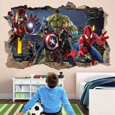 a boy sitting on the floor in front of a wall mural with avengers and spider - man