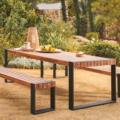 a wooden table with two benches next to it and some fruit on the plate near by