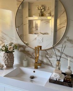 a bathroom sink with a mirror above it and flowers in vases on the counter