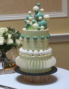 a three tiered cake sitting on top of a table next to a vase filled with flowers