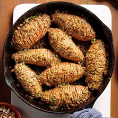 a pan filled with cooked carrots on top of a cutting board next to a bowl of nuts