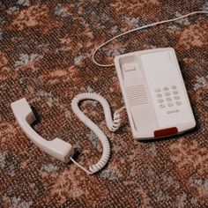 an old phone is laying on the floor next to it's corded telephone