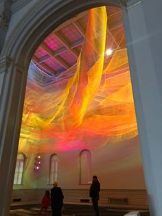 two people are standing in front of an art installation that looks like it is flying through the air