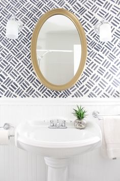 a white sink sitting under a bathroom mirror next to a wall mounted faucet