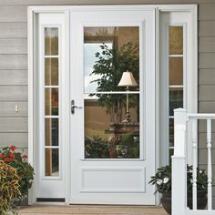 a white front door with a lamp on it and potted plants in the window