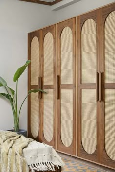 a large wooden cabinet sitting next to a plant on top of a rug in a room