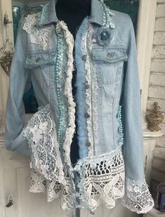 a denim jacket with lace trims and buttons on the front, hanging from a door