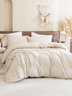 a bed with white linens and pillows in a large room next to a plant