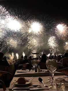 fireworks are lit up the night sky over a restaurant table