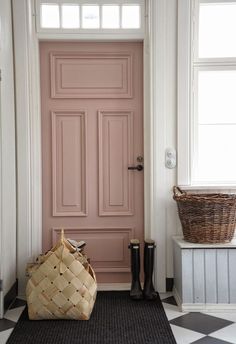 a pink door in the corner of a room with a basket on the floor next to it