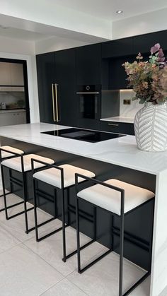 a kitchen with black cabinets, white countertops and stools next to an island