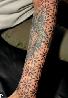 a man's arm with tattoos on it and an image of a bird in the middle