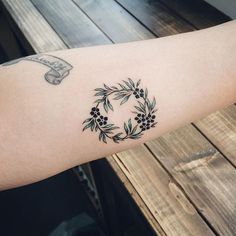 a woman's arm with a tattoo on it that has flowers and leaves in the center